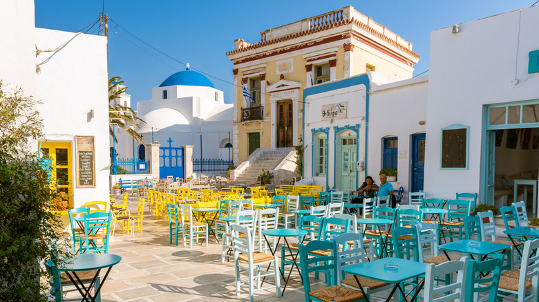 Colorful tables and chairs with whitewashed buildings in Hora town square on Serifos, Greece