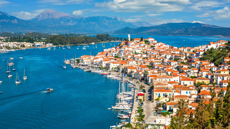 A town of white buildings and red-tiled roofs meets the blue sea in Greece