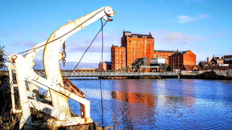 Blue water dock with fishing apparatus and red brick heritage center in background
