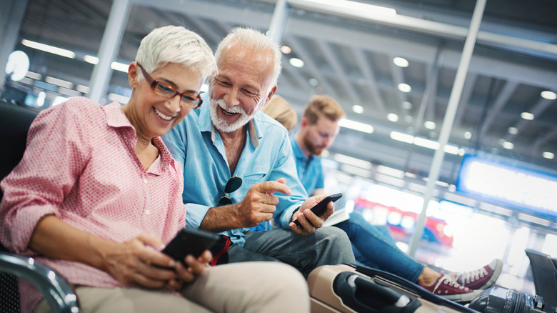 Elderly couple at the airport on their phones