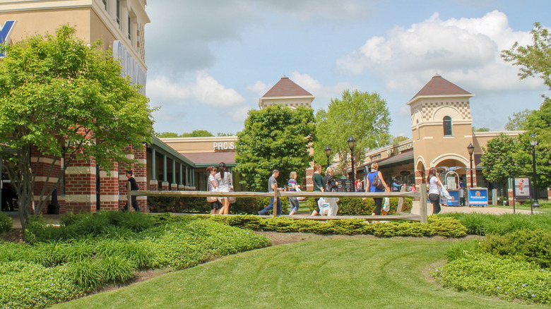 Shoppers walk beside manicured gardens and stores at Grove City Premium Outlets.