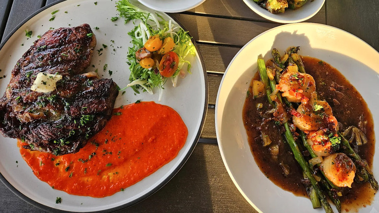 Steak and scallops on two plates at restaurant