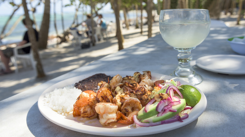 A plate of Mexican food with a margarita and a beach in the background in Tulum, Mexico
