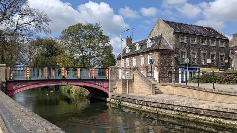 A historic bridge over a canal next to a stone building in Thetford