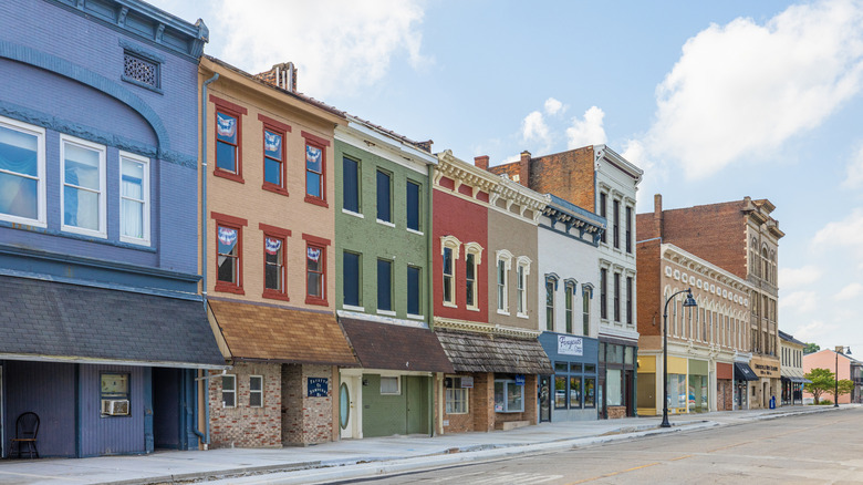 A row of colorful businesses along an empty street on a bright cloudy day in Connersville, Indiana.