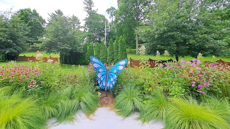 A garden inside Matter Park in Indiana, with colorful flowers with a large blue butterfly art installation, surrounded by lush greenery.