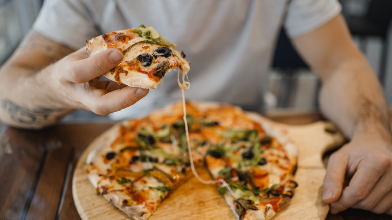 Man eating a pizza on a wooden table
