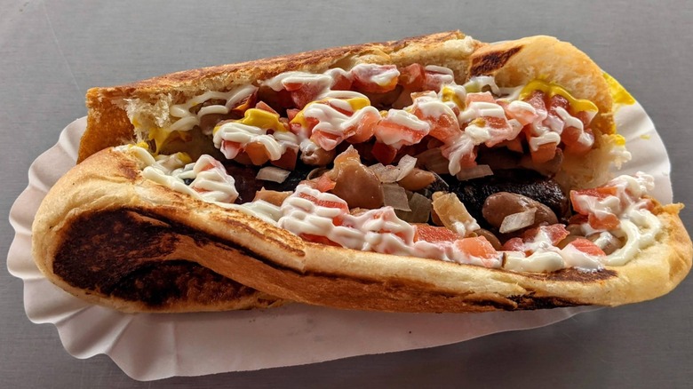 Toasted Sonoran hot dog with toppings on metal table at Ruiz's Tucson