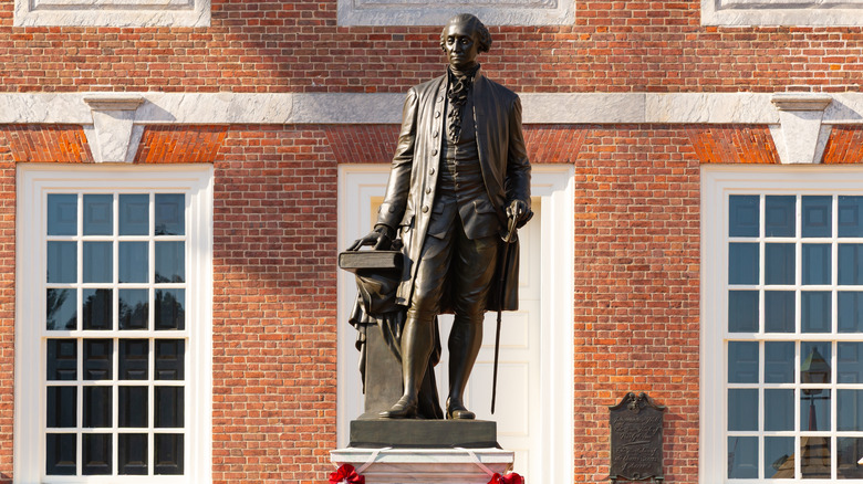 A statue of George Washington with book and walking stick is displayed in front of Independence Hall in Philadelphia