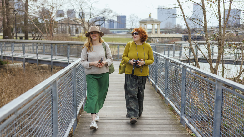 Two women in fashionable outfits walk through a Philadelphia park
