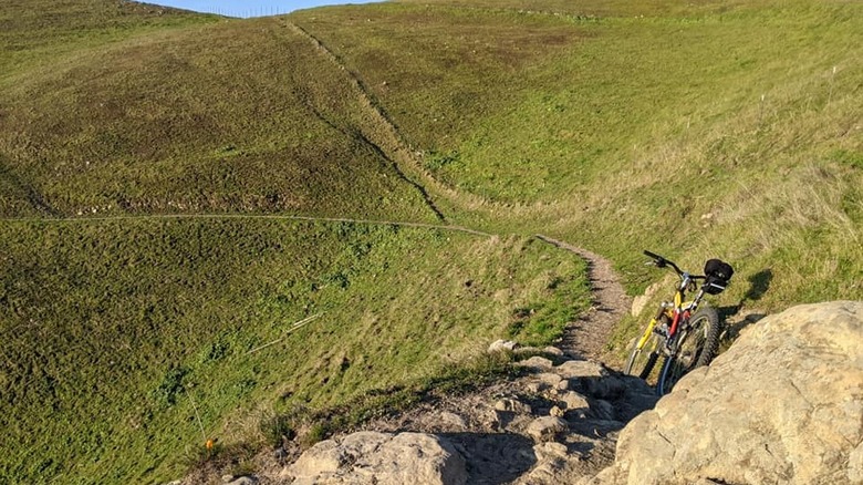 A bike leans against a rock on the grassy slopes of Mission Peak, California
