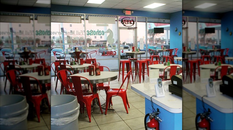 The interior of Seahorse Grill decorated with blue walls and red metal chairs