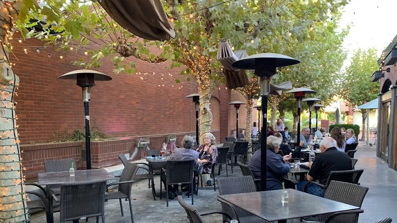 Shoppers dine on a red-brick patio beneath sycamores at Pavilions Shopping Center in Sacramento.