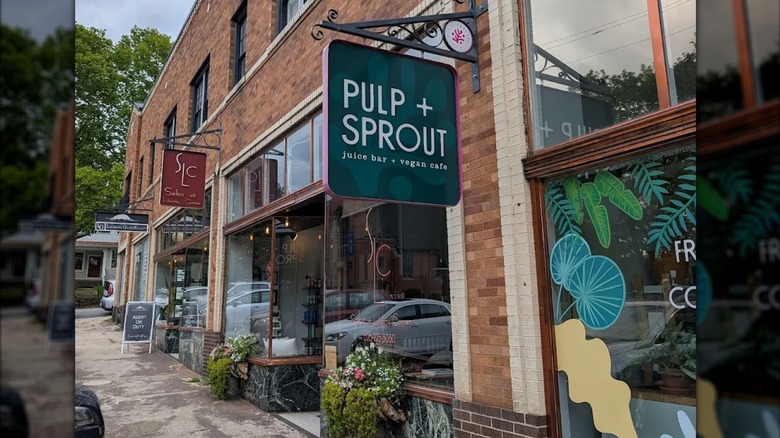 The exterior of Pulp + Sprout, housed in a charming brick building surrounded by greenery and flowers in Asheville, North Carolina