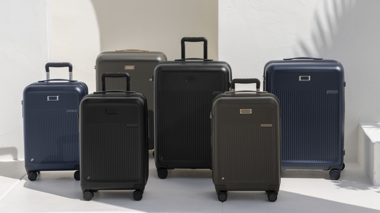Six Sympatico carry-on suitcases from Briggs & Riley in various colours lined up against a cream background