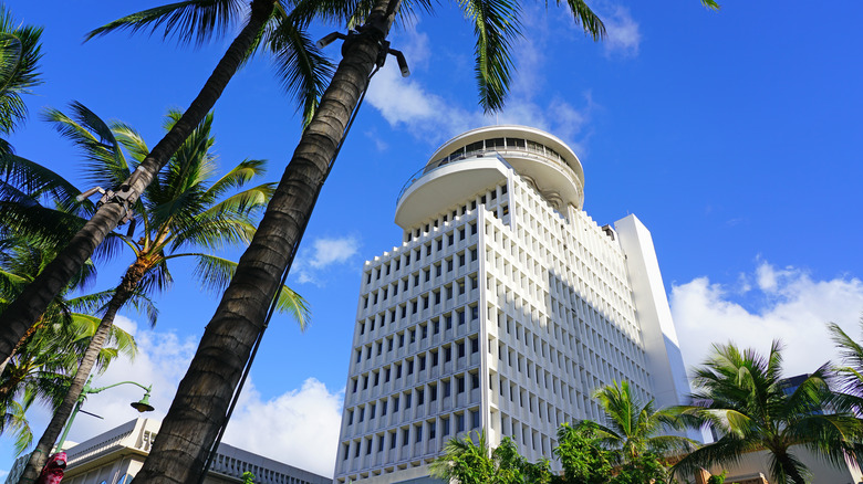 Waikiki Business Plaza stands framed by palm trees beneath a blue sky