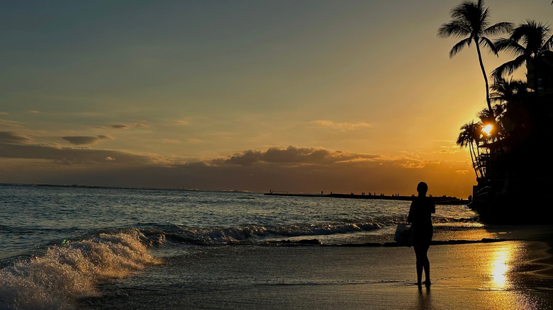 Person standing on beach on Oahu at sunset