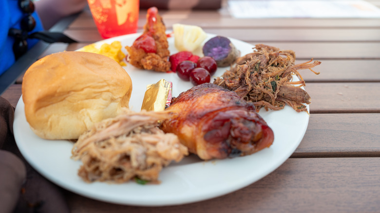 Buffet plate with kalua pork, teriyaki chicken, crispy chicken strips, Molokai purple sweet potato, fruit and a bread roll at the Myths of Maui luau