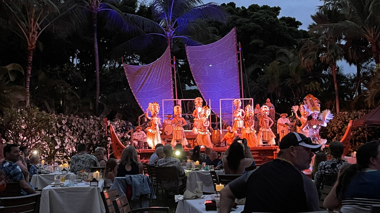 View of illuminated performers in the dark during the luau at Aulani, a Disney Resort and Spa