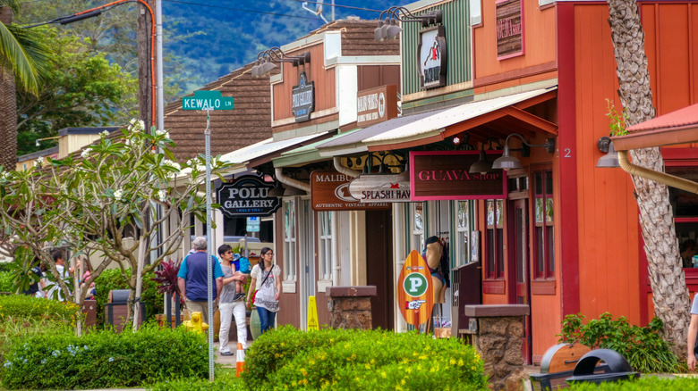 Tourists walking along a row of colorful shopfronts with signs