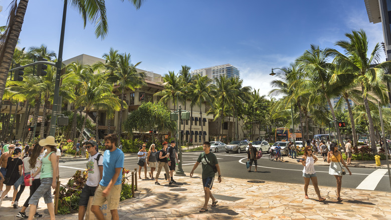 Pedestrians walking down Waikiki's palm tree-lined streets