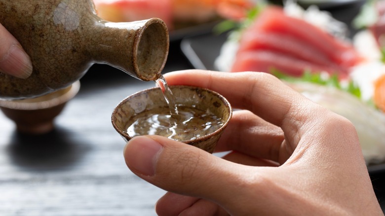 Sake being poured into a small hand-held bowl