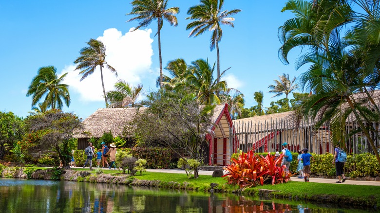 Traditional thatched homes stand by the water at the Polynesian Cultural Center in Hawaii