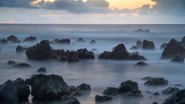Dawn sky over waves and rough volcanic rocks in, Laupāhoehoe, Hawaii