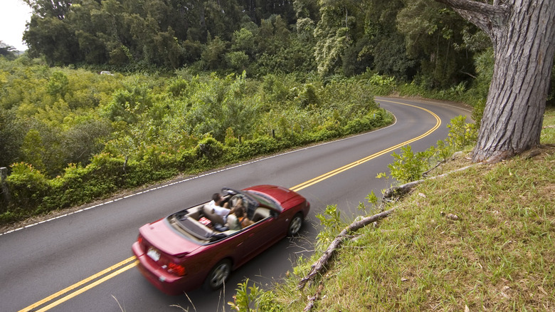 a red convertible approaching a steep turn on the Road to Hana