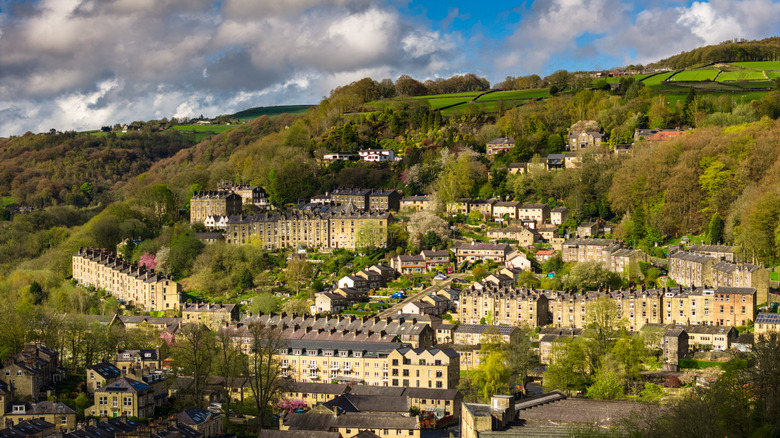 An aerial view of honey-colored terraced homes stacked upon a hillside in Hebden Bridge in England's Calder Valley