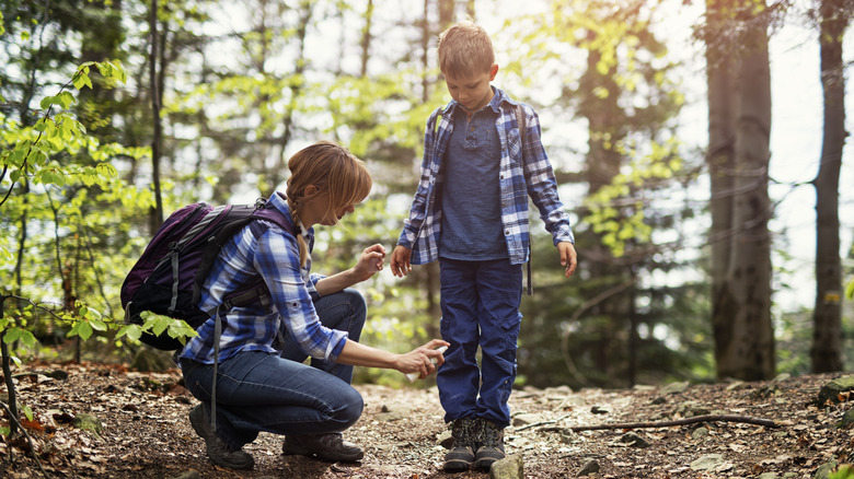Mother sprays child with insect repellent
