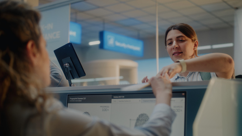 A woman shows her ID to a TSA agent at an airport security checkpoint