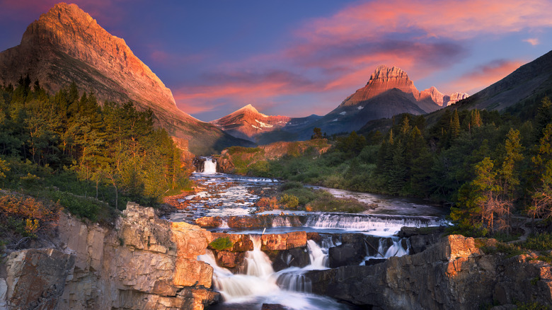 Colorful skies over mountains, forest, and stream