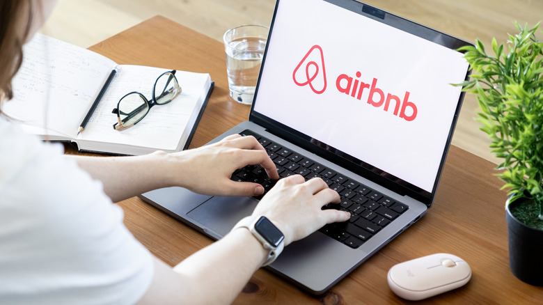 Close-up of a woman's hands as she searches for something on the Airbnb website, which is opened on her laptop.