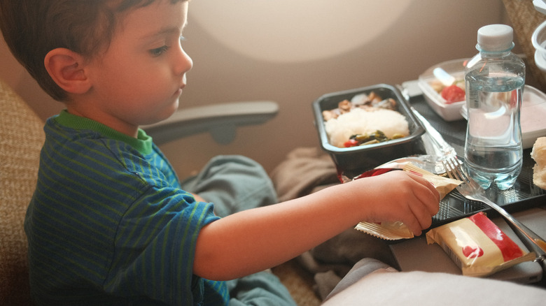 Small child eating an in-flight meal on a tray