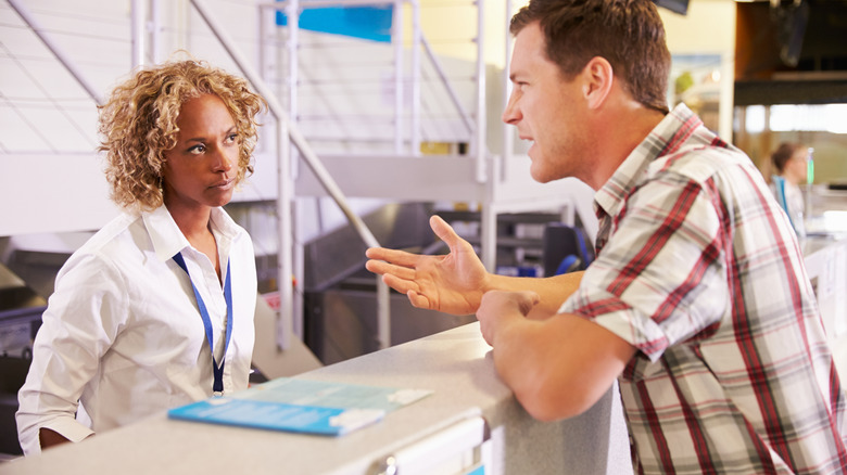 Traveler speaking to an airport customer service representative at a desk
