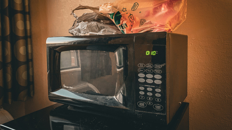 A microwave stands on a mini-fridge in a hotel room