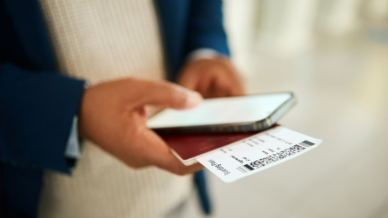 Holding boarding pass, phone, and passport