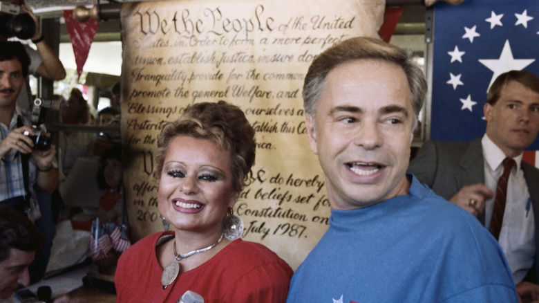 Tammy Faye Bakker and Jim Bakker stand in front of poster of the U.S. Constitution