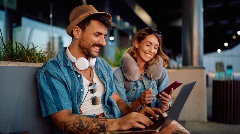 Travelers on their computer and using cell phone at the airport