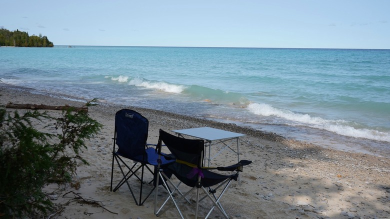 Two camping chairs and a table overlooking the blue water at Fisherman's Island State Park