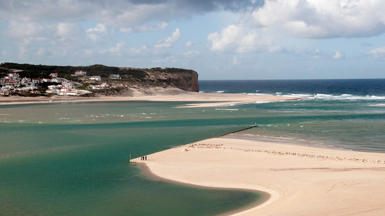 a sandy beach protruding out into a sea on the coast of portugal