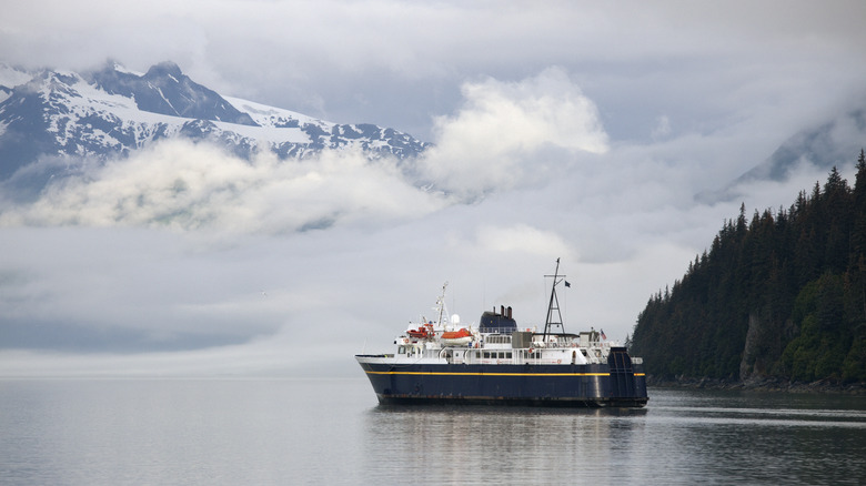 A ferry surrounded. by mointains and woods