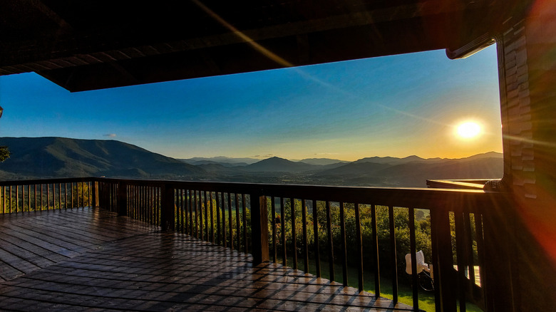 A view from a cabin's porch with the sun in the background