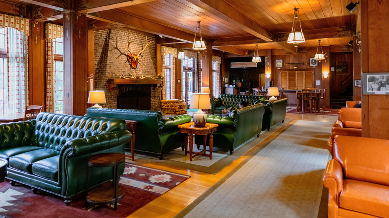 Interior of Lake Quinault Lodge featuring green, orange, and warm colors on the furniture and wooden finishings, with a large fireplace on the center left wall