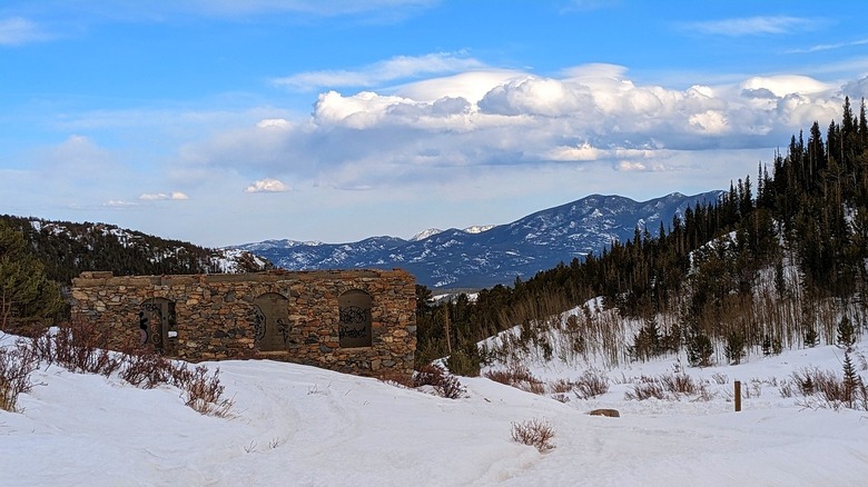 Wintry scene of abandoned structure and mountain backdrop in Caribou, Colorado