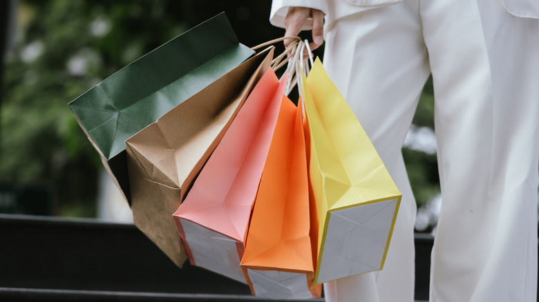 Someone wearing a white suit and carrying colorful shopping bags