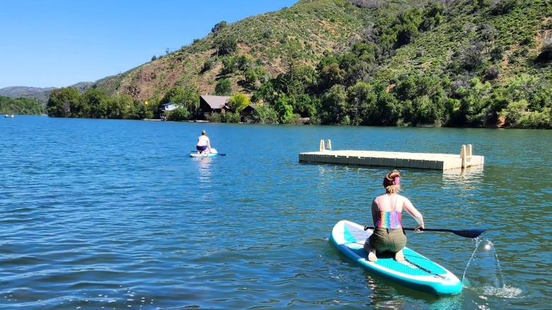 Two women kneel on paddle boards at Blue Lakes, California.