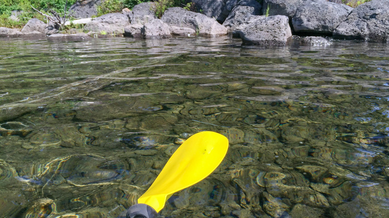 An oar is lifted above the clear waters of Lake Waldo