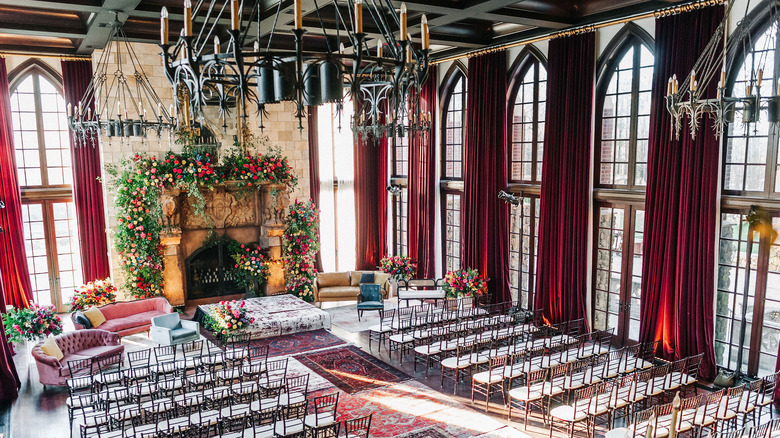 Elegant hall lined with chairs and flowers for a wedding ceremony.
